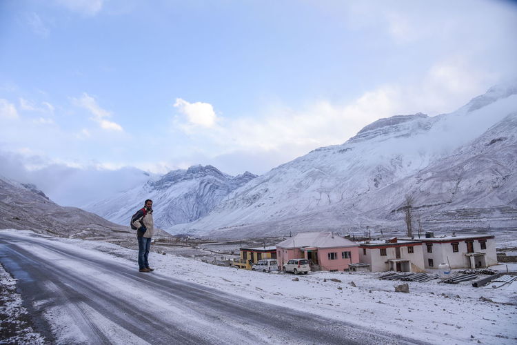 Man standing on road against snowcapped mountains during winter
