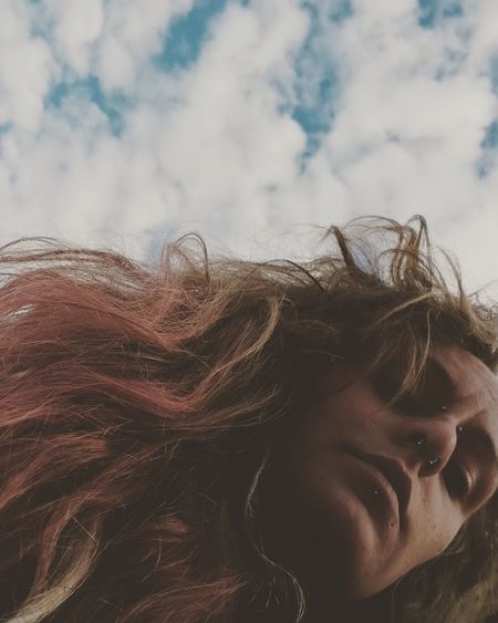 Low angle view of woman against cloudy sky