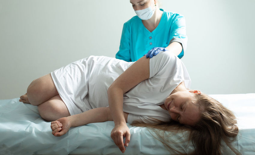 Portrait of doctor examining patient lying on bed at home