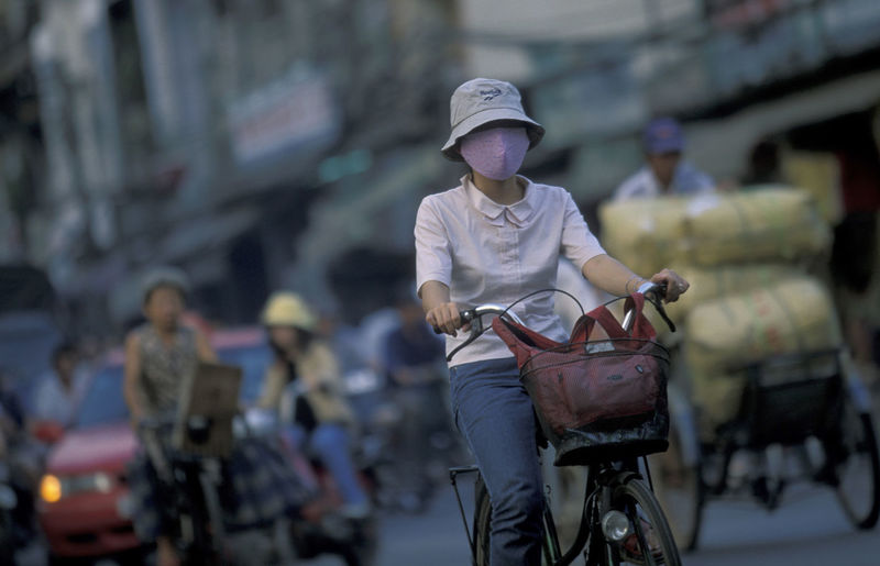 Woman wearing facial mask while riding bicycle on street