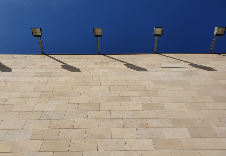 View of empty tiled floor  and lightsagainst blue sky