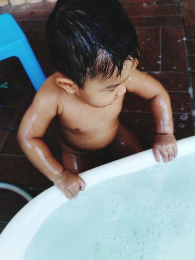 Close-up of shirtless baby boy having bath