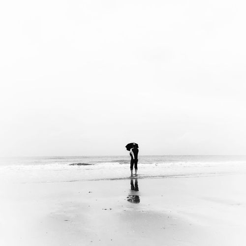 Man walking on beach against clear sky
