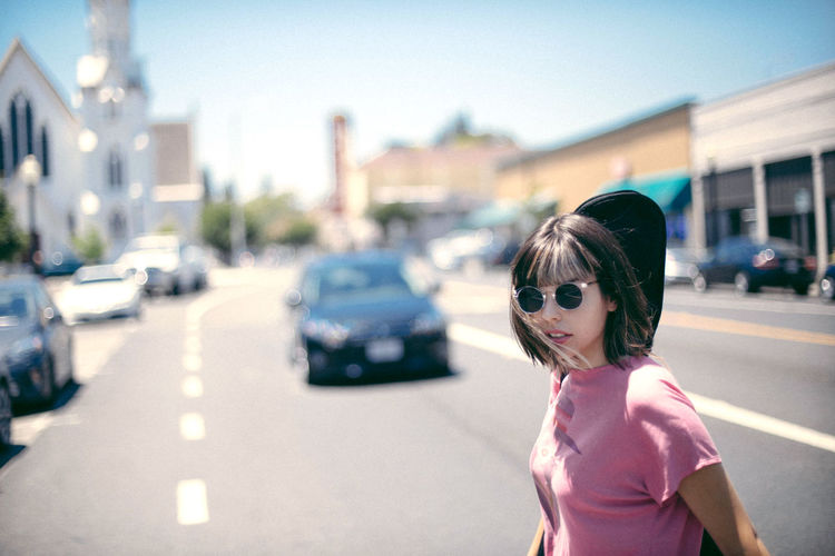 Portrait of woman crossing road in city during sunny day