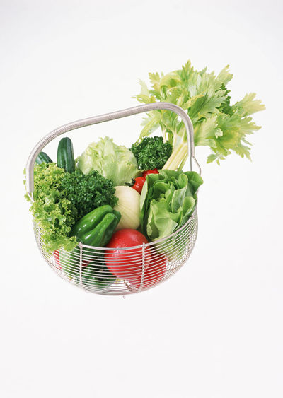 Vegetables in basket against white background