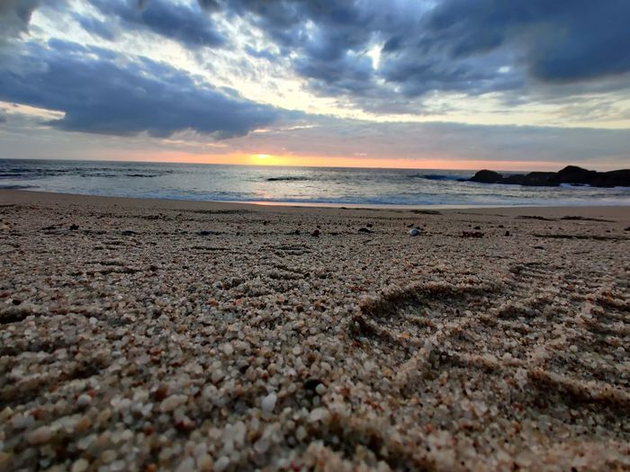 Surface level of beach against sky during sunset