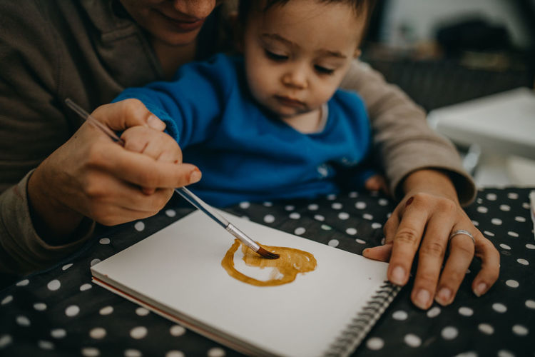 High angle view of child painting with mother on table