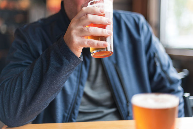 Midsection of man drinking beer in restaurant