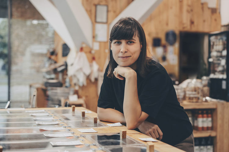 Smiling store owner leaning on counter in zero waste shop