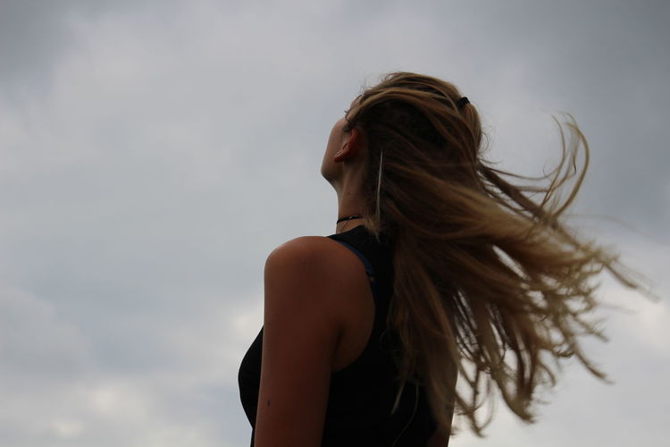 Low angle view of woman with tousled hair looking at sky