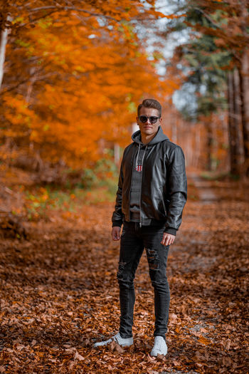 Portrait of young man standing on autumn tree