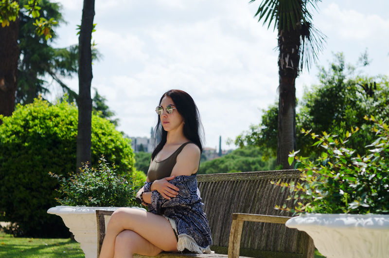 Portrait of young happy brunette asian woman relaxing in city, park. summer vacation. travel