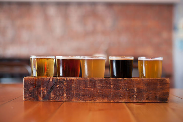 Close-up of various beer glass in wooden tray on table