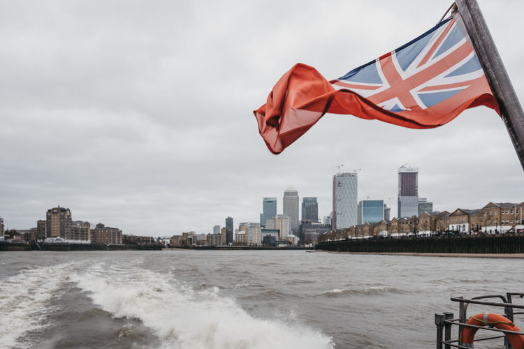 British flag waving on boat in river against sky