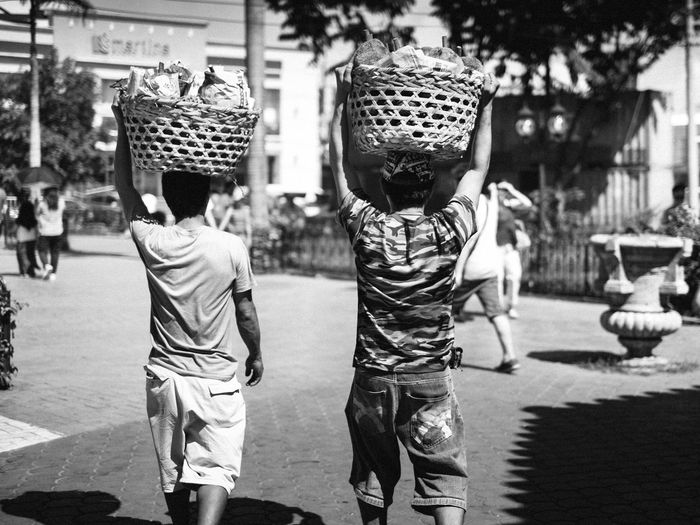 Rear view of men carrying basket while walking on road
