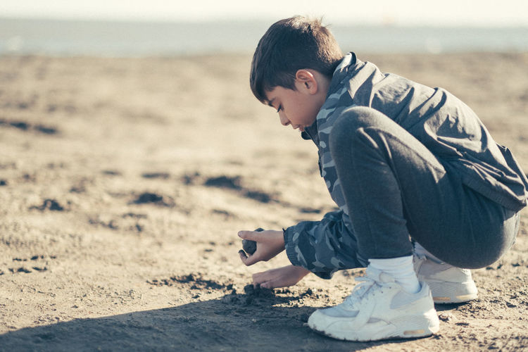 Side view of boy playing at beach