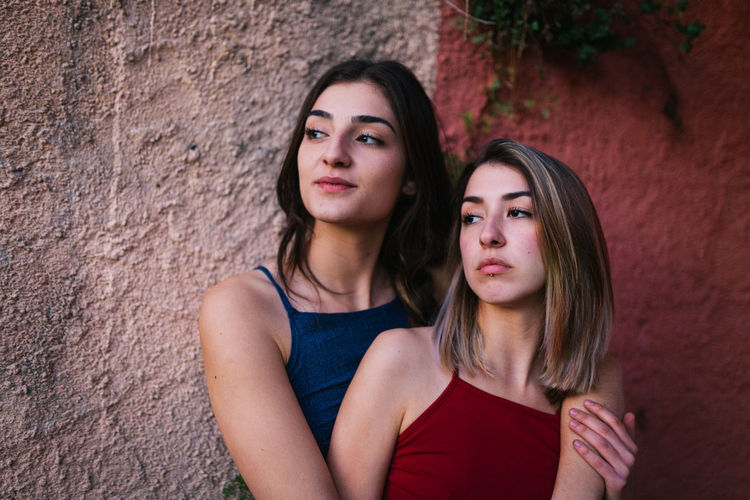 Lesbian couple standing against wall
