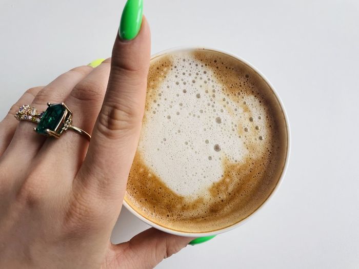Cropped hand holding coffee against white background