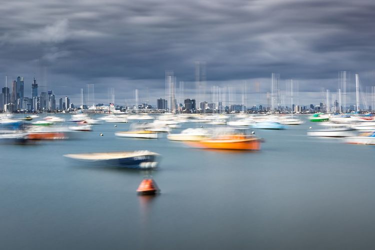 Boats moored at harbor in city against sky