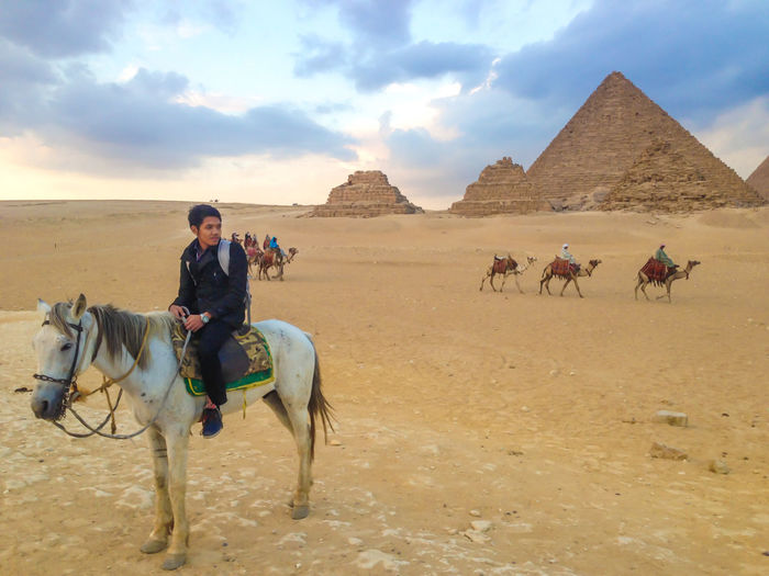 Group of people riding horse on desert, giza egypt