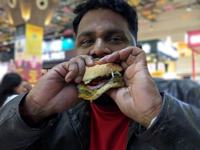 Portrait of man eating burger at restaurant