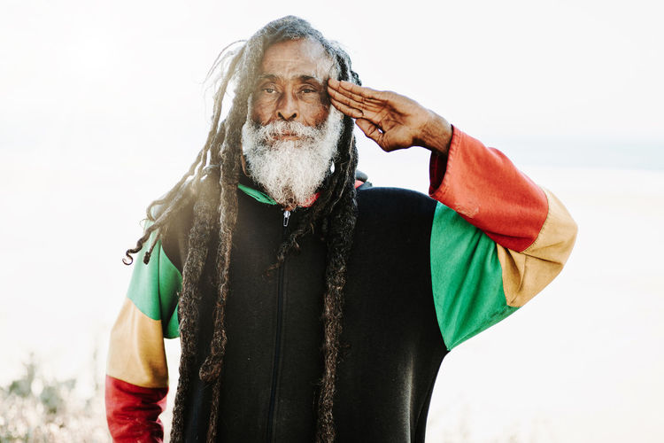 Portrait of old rastafari with dreadlocks looking at the camera in the nature with white background