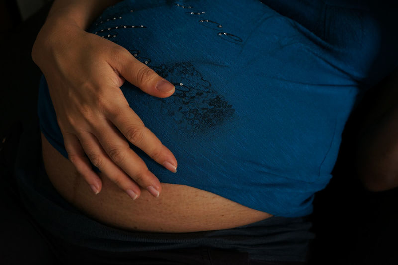 Midsection of pregnant woman touching belly
