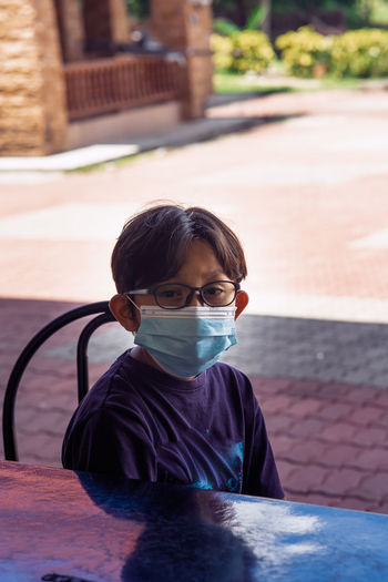 Portrait of boy with mask sitting outdoors