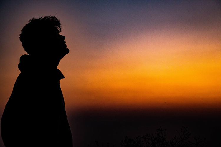 Silhouette man standing against orange sky