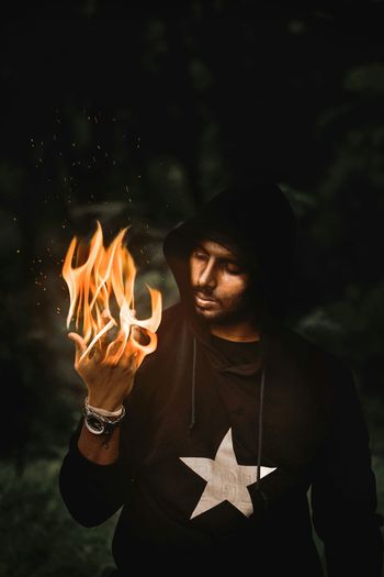 Man holding burning fire at night