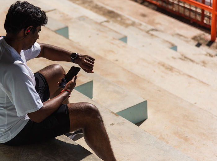 High angle view of man using smart phone sitting outdoors