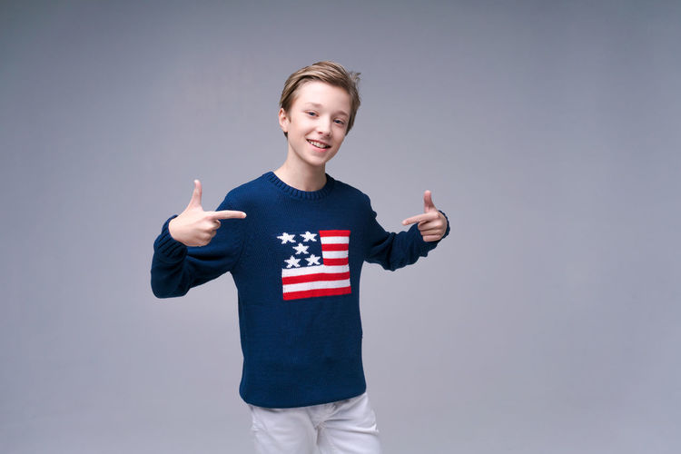 Portrait of boy with arms raised standing against blue background