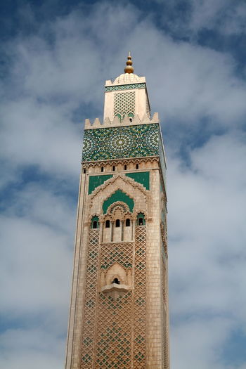 Low angle view of mosque hassan ii minaret against cloudy sky