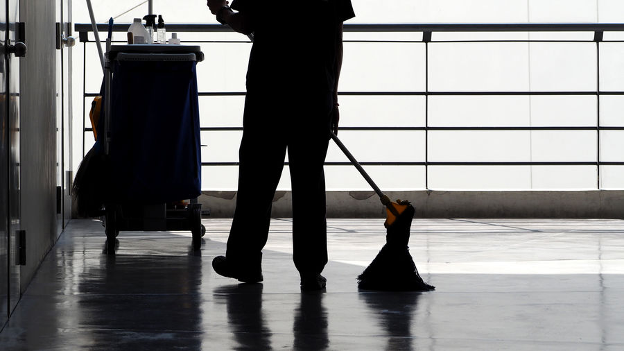 Low section of silhouette man cleaning floor
