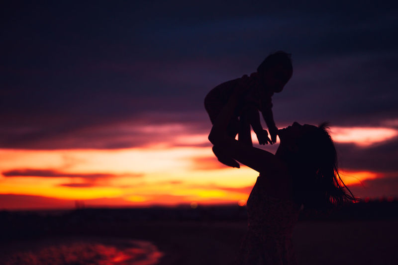 Silhouette people standing on field against sky during sunset