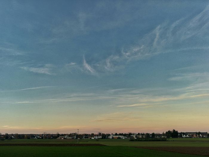 Scenic view of grassy field against sky at sunset