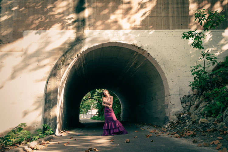 Woman standing in tunnel against building