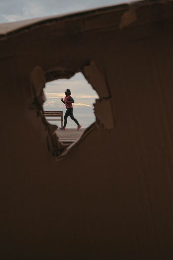 Woman jogging seen through hole