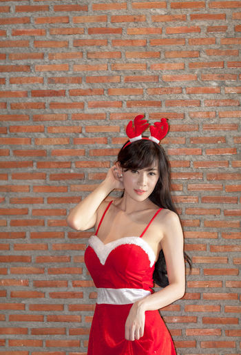 Young woman standing against brick wall