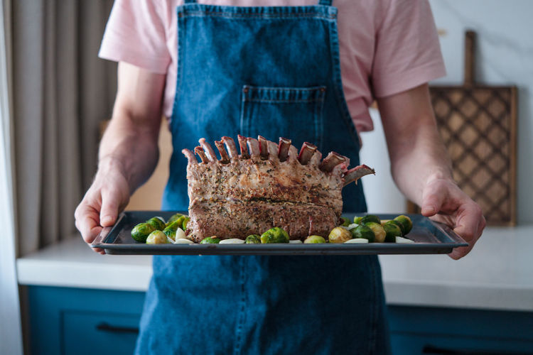Roasted rack of lamb on a tray in the hands of the chef