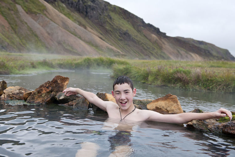 Teenage boy enjoying a bath at geothermal hot spring in iceland