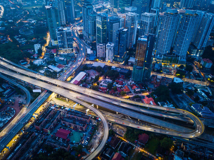 Aerial view of illuminated highway amidst buildings at night