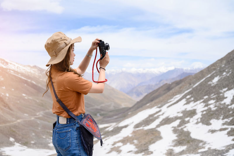 Man photographing with camera on mountain against sky