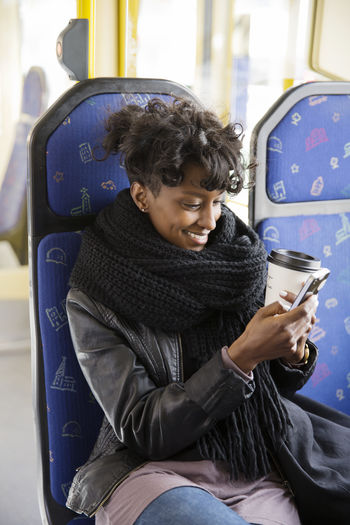 Young woman using mobile phone while sitting in bus
