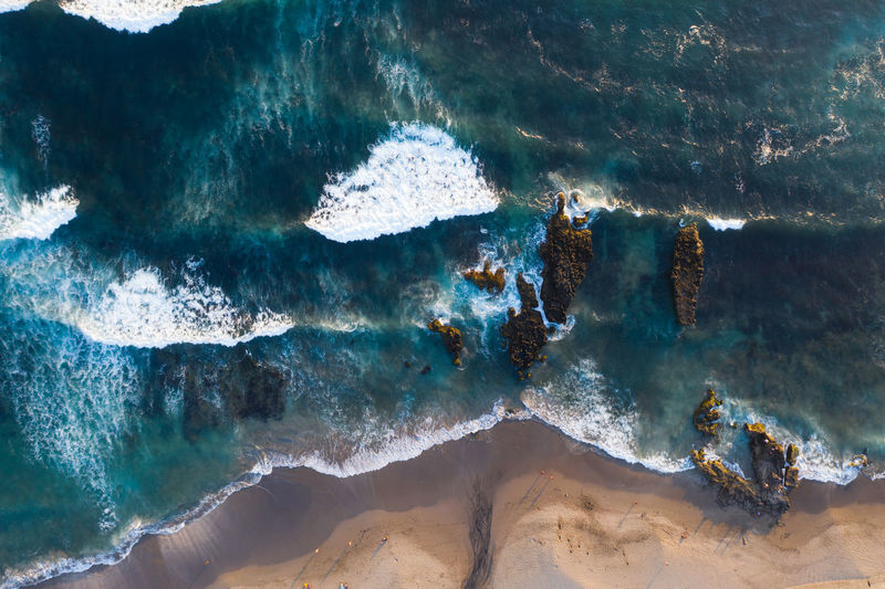 Aerial view of waves splashing on rocks at beach