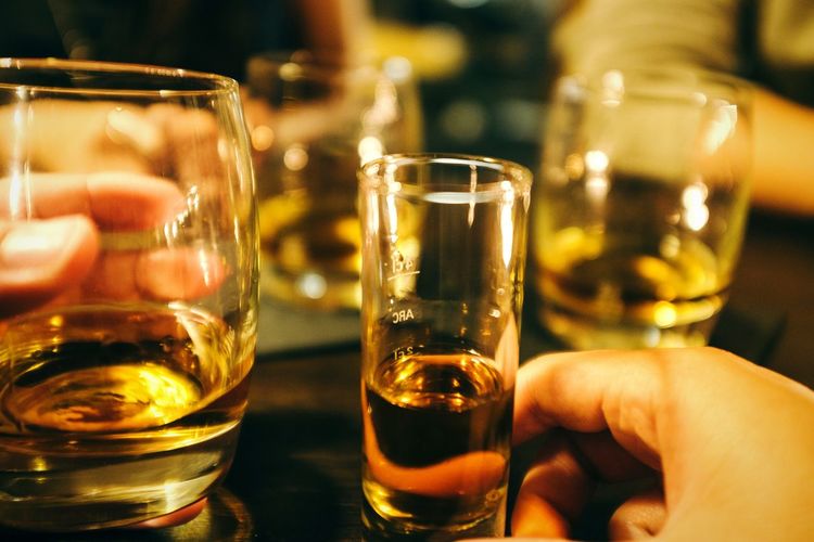 Cropped hand of people holding alcohol at table