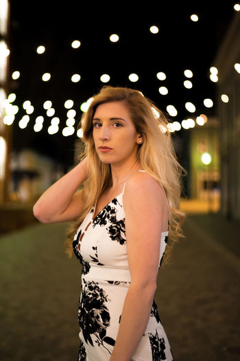 Portrait of young woman against illuminated lights