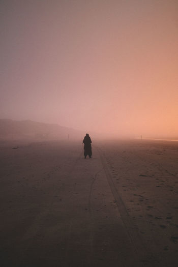 Silhouette man at beach against sky during sunset