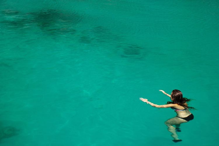 Aerial view on women swimming alone in turquoise water 