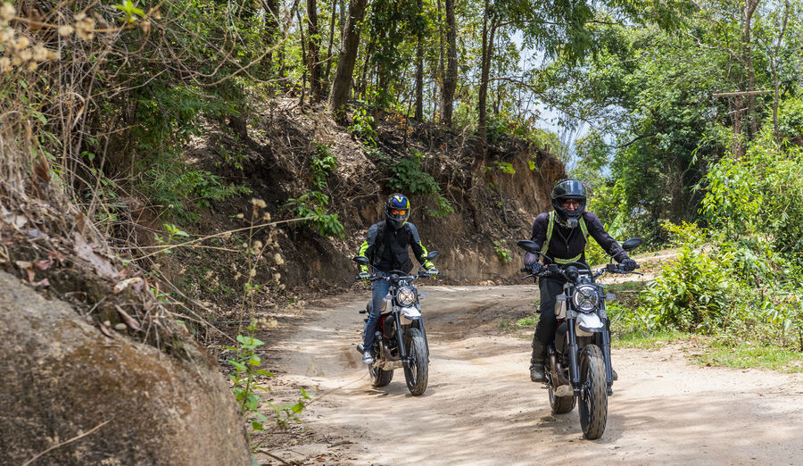 Two friends riding their scrambler motorcycles through forrest